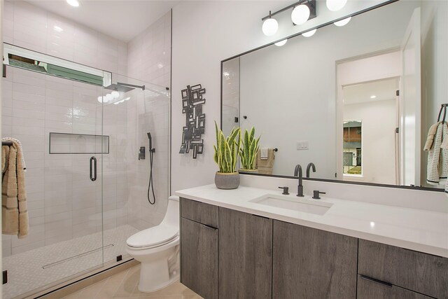 bathroom featuring tile patterned flooring, vanity, a shower with shower door, and toilet