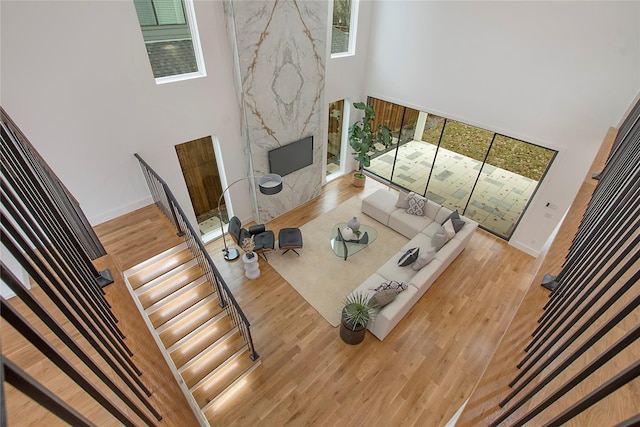 living room with hardwood / wood-style floors, a fireplace, and a high ceiling