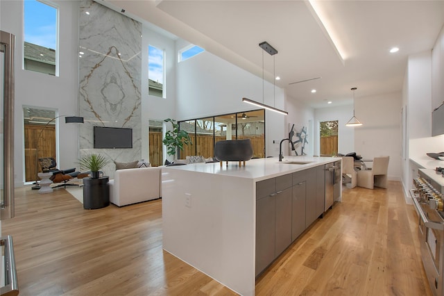 kitchen featuring gray cabinetry, pendant lighting, sink, a large island, and light hardwood / wood-style floors