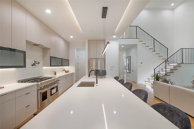 kitchen with hanging light fixtures, sink, stainless steel appliances, and light wood-type flooring