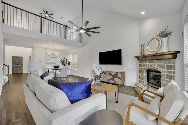 living room featuring a fireplace, ceiling fan with notable chandelier, a high ceiling, and hardwood / wood-style flooring