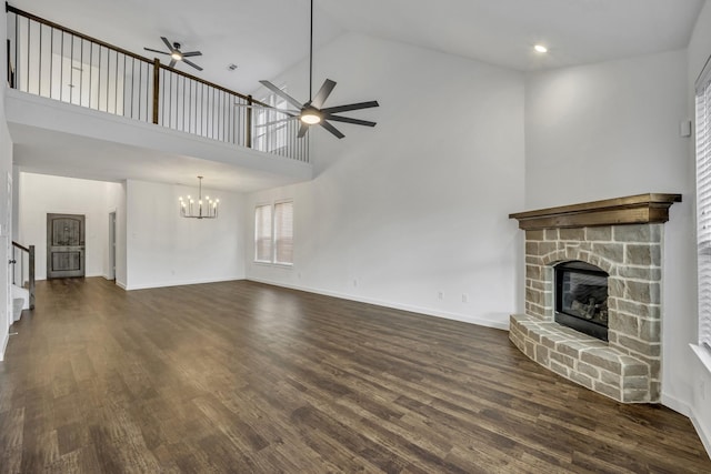 unfurnished living room with ceiling fan with notable chandelier, a fireplace, high vaulted ceiling, and dark wood-type flooring