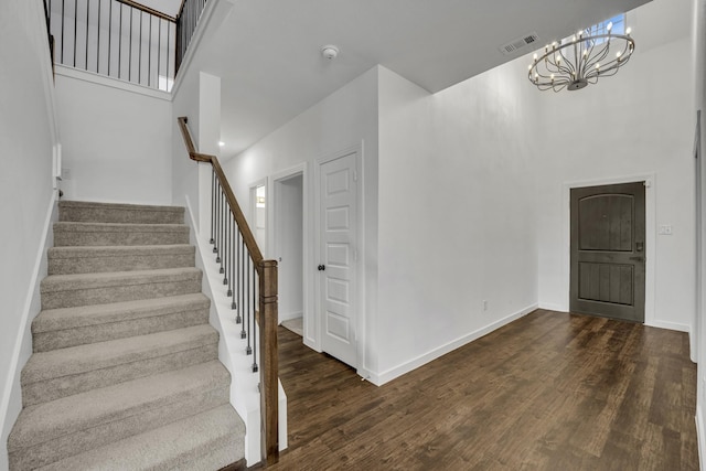 stairs with a chandelier, wood-type flooring, and a towering ceiling