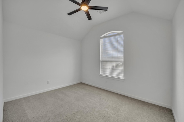 carpeted spare room featuring ceiling fan and vaulted ceiling