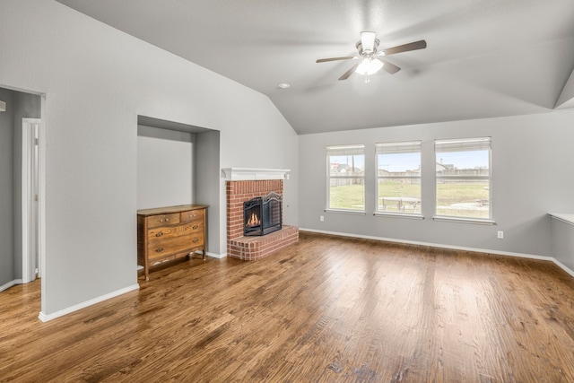 unfurnished living room featuring lofted ceiling, a brick fireplace, hardwood / wood-style flooring, and ceiling fan