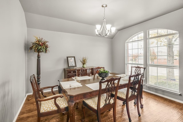 dining room featuring vaulted ceiling, dark wood-type flooring, and a notable chandelier