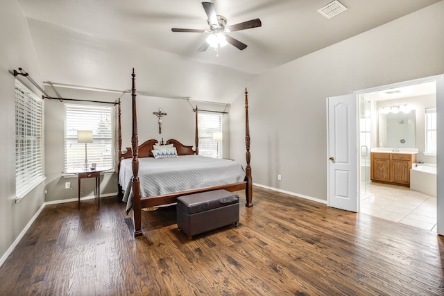 bedroom with multiple windows, vaulted ceiling, light hardwood / wood-style floors, and ensuite bathroom