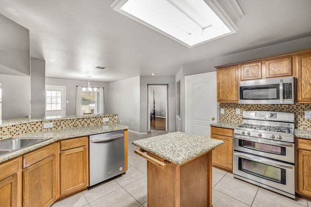 kitchen featuring backsplash, stainless steel appliances, a kitchen island, and light tile patterned floors