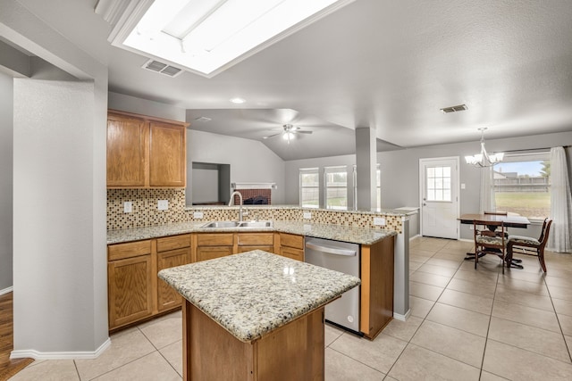 kitchen with a center island, sink, stainless steel dishwasher, and decorative light fixtures