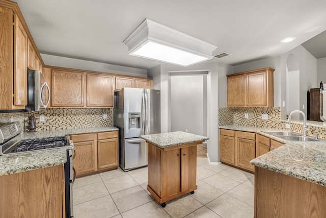 kitchen with sink, a center island, light tile patterned floors, stainless steel appliances, and light stone countertops