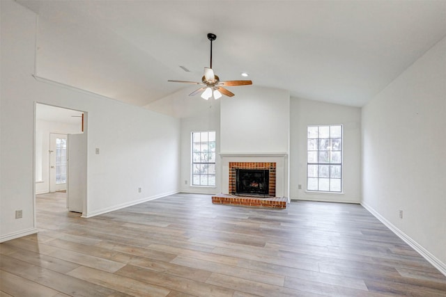 unfurnished living room featuring a fireplace, light wood-type flooring, ceiling fan, and lofted ceiling