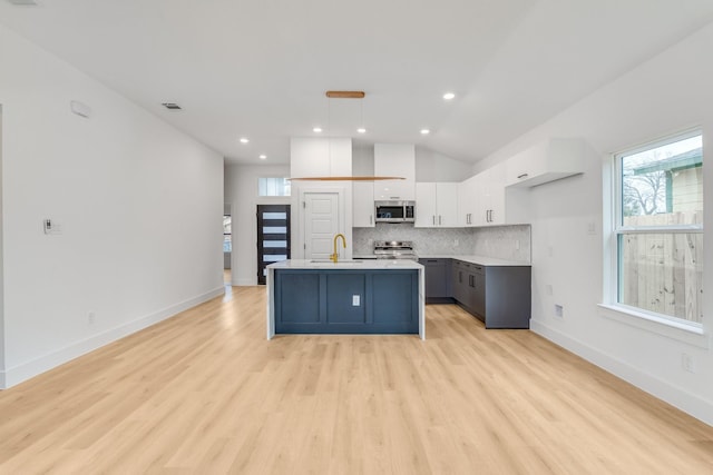 kitchen featuring stainless steel appliances, white cabinets, gray cabinets, hanging light fixtures, and an island with sink