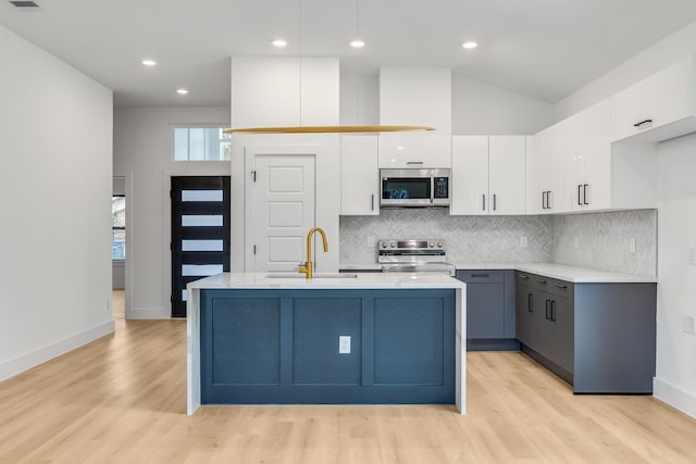 kitchen with white cabinets, a center island with sink, sink, gray cabinets, and appliances with stainless steel finishes