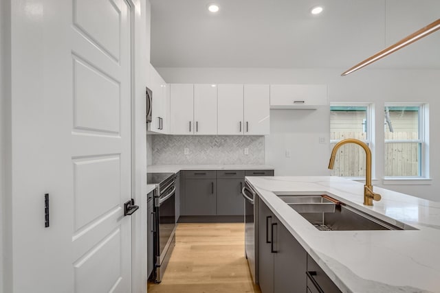 kitchen with gray cabinetry, sink, light stone countertops, white cabinetry, and stainless steel appliances