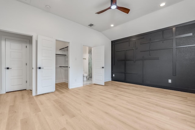 unfurnished bedroom with connected bathroom, ceiling fan, vaulted ceiling, and light wood-type flooring