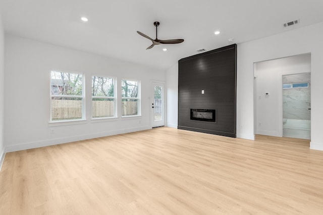 unfurnished living room with a fireplace, light wood-type flooring, and ceiling fan