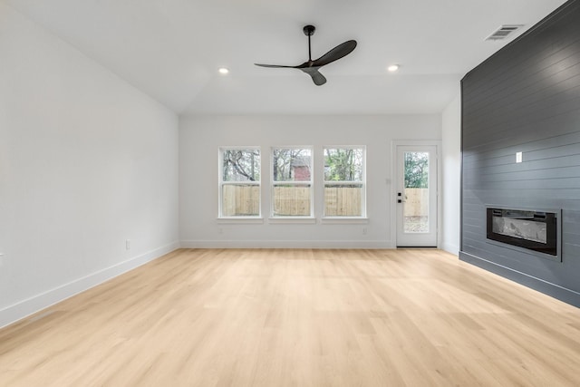 unfurnished living room featuring ceiling fan, light hardwood / wood-style flooring, a fireplace, and vaulted ceiling