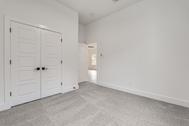 unfurnished bedroom with light carpet and a closet