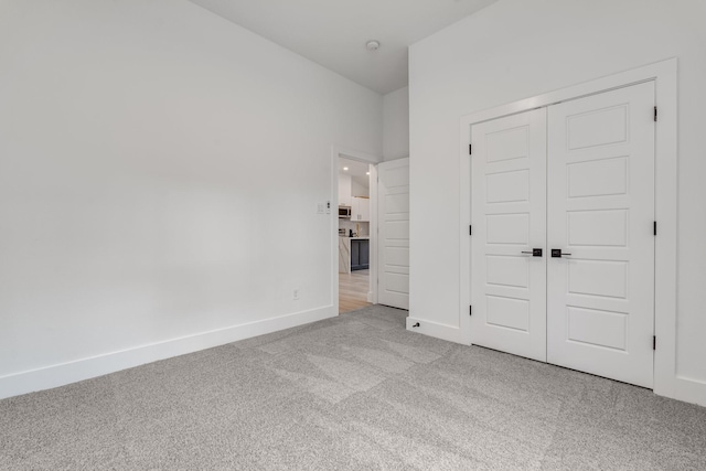 unfurnished bedroom featuring light colored carpet and a closet