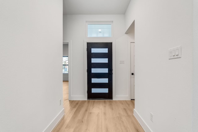 entryway with a towering ceiling and light wood-type flooring