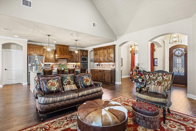 living room with dark hardwood / wood-style floors, lofted ceiling, and an inviting chandelier