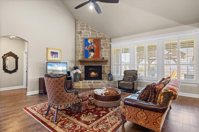 living room with dark hardwood / wood-style flooring, high vaulted ceiling, a stone fireplace, and ceiling fan