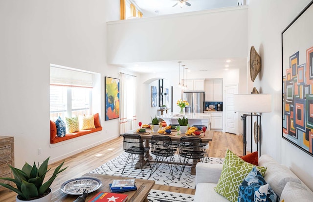 dining area with a high ceiling, ceiling fan, and light hardwood / wood-style floors