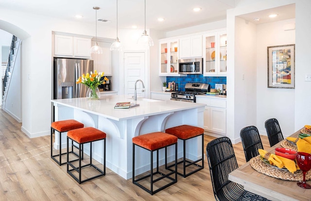 kitchen with stainless steel appliances, white cabinets, hanging light fixtures, and sink