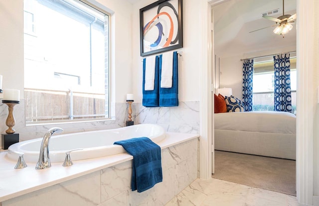 bathroom featuring ceiling fan, tiled tub, and plenty of natural light