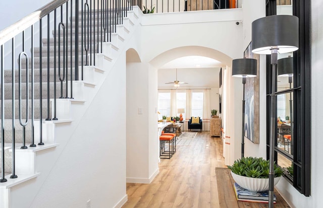 hall with a towering ceiling and light hardwood / wood-style floors