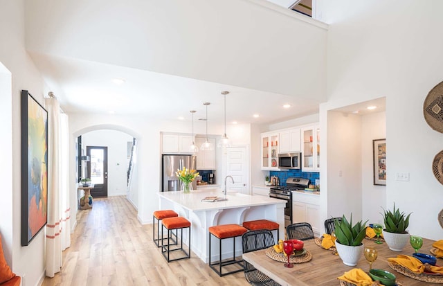 kitchen featuring appliances with stainless steel finishes, pendant lighting, an island with sink, and white cabinetry