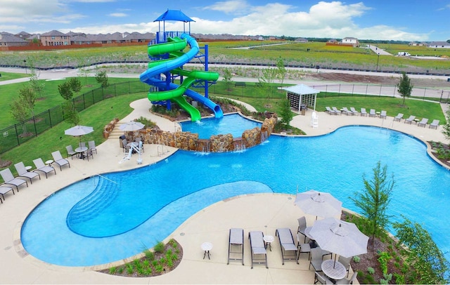 view of pool with a water slide, a playground, and a yard