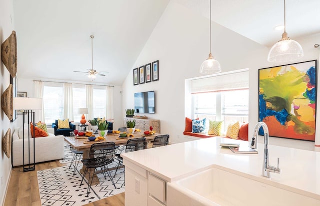 kitchen featuring decorative light fixtures, light wood-type flooring, ceiling fan, and sink