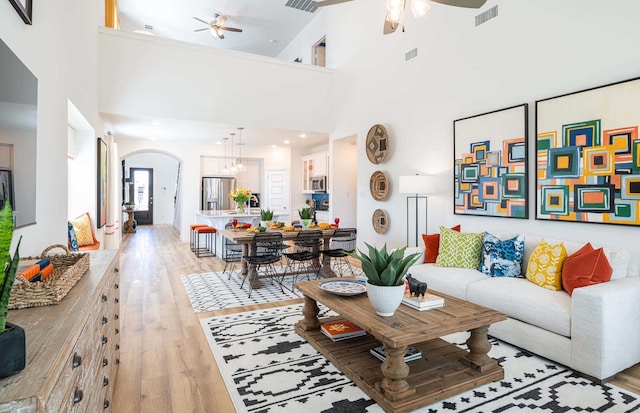 living room with a towering ceiling, ceiling fan, and hardwood / wood-style floors