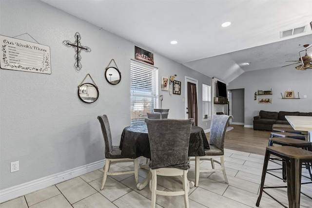 dining room with ceiling fan, lofted ceiling, and light wood-type flooring