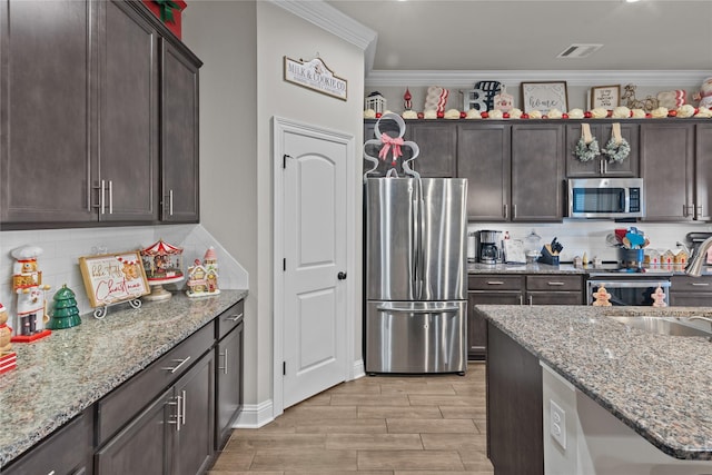 kitchen featuring backsplash, sink, light stone countertops, appliances with stainless steel finishes, and dark brown cabinets