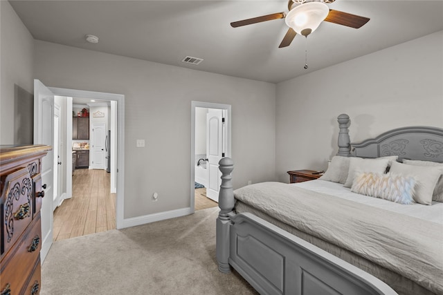 bedroom with ceiling fan, ensuite bathroom, and light carpet