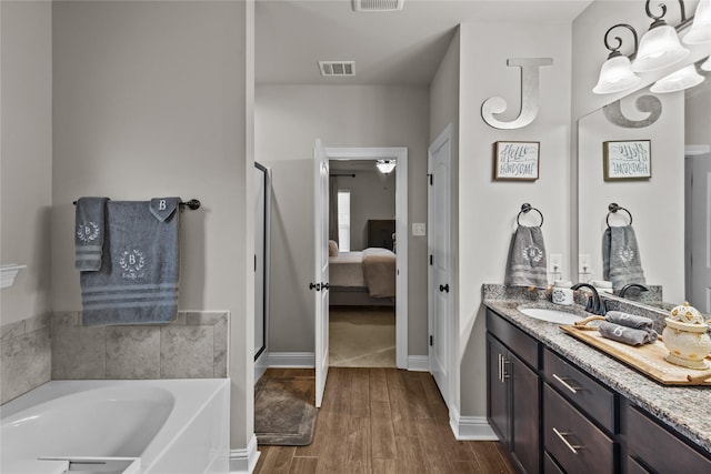 bathroom with vanity, hardwood / wood-style floors, and a tub to relax in