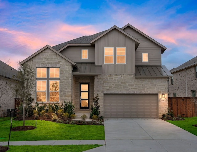 view of front of house featuring a yard, a standing seam roof, fence, a garage, and driveway