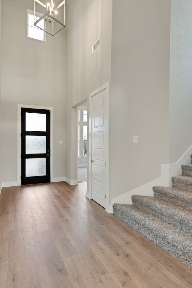 foyer featuring wood finished floors, visible vents, plenty of natural light, and stairs