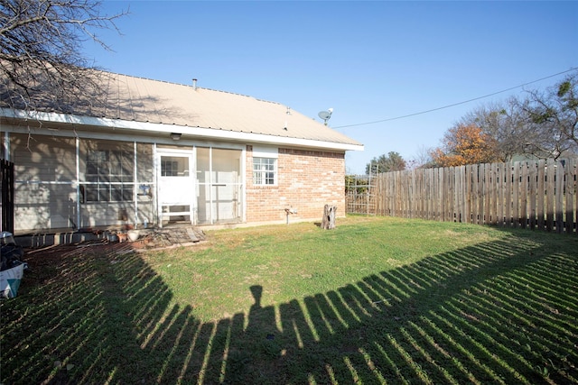 back of property featuring a lawn and a sunroom