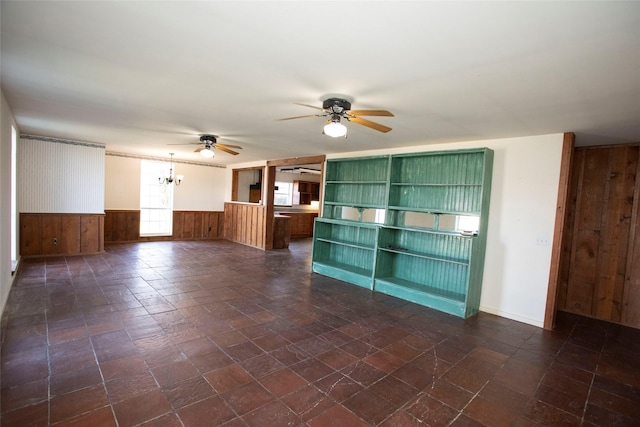 unfurnished living room with ceiling fan and wood walls