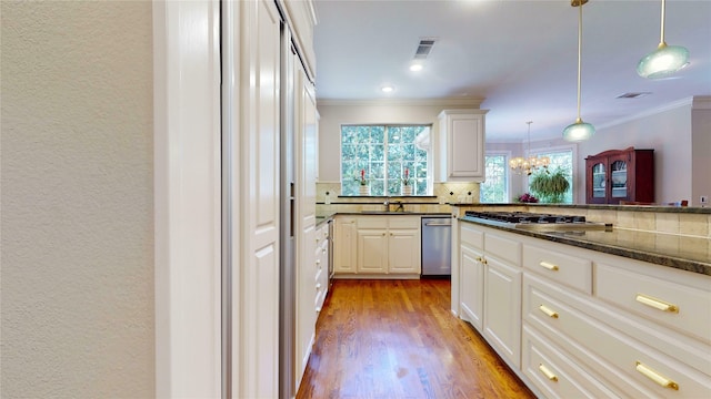 kitchen with pendant lighting, sink, appliances with stainless steel finishes, tasteful backsplash, and white cabinetry