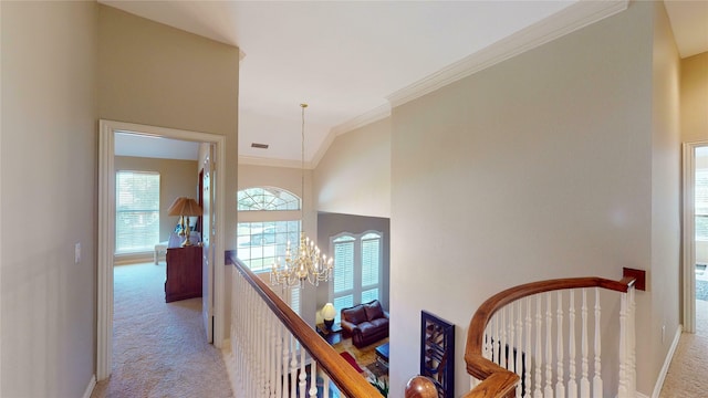 hallway featuring ornamental molding, light colored carpet, high vaulted ceiling, and a notable chandelier