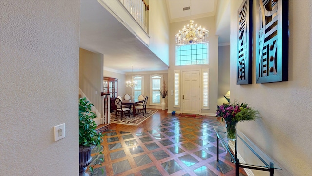 foyer featuring a chandelier, a towering ceiling, and ornamental molding