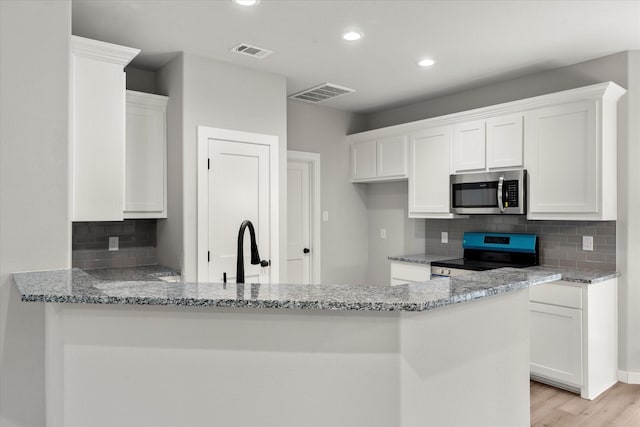 kitchen featuring white cabinets, kitchen peninsula, and black electric range