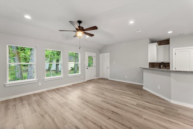 unfurnished living room with light wood-type flooring, vaulted ceiling, and ceiling fan