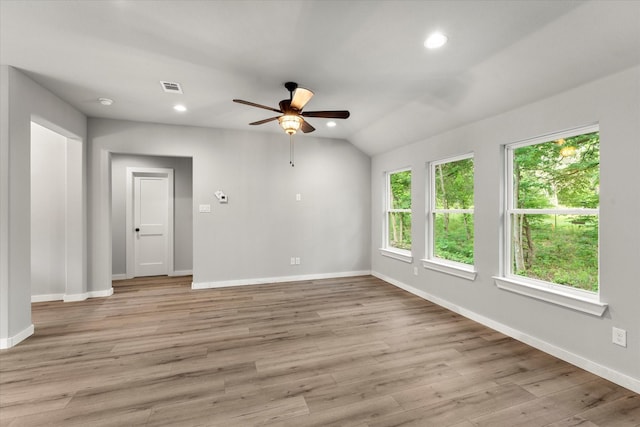 empty room with ceiling fan, vaulted ceiling, and light wood-type flooring