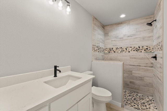 bathroom with toilet, vanity, and tiled shower