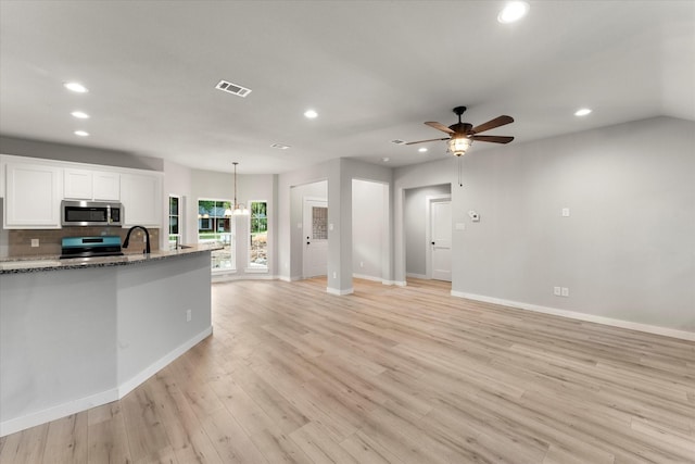 kitchen featuring light stone countertops, ceiling fan with notable chandelier, decorative light fixtures, white cabinets, and range